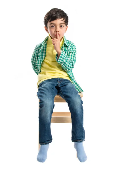 Niño haciendo gesto de silencio en silla de madera sobre fondo blanco —  Fotos de Stock