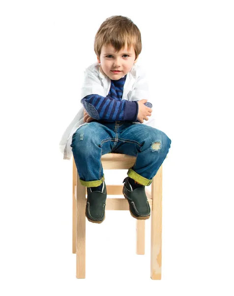 Niño con los brazos cruzados en una silla de madera — Foto de Stock