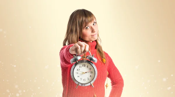 Chica joven sosteniendo un reloj antiguo sobre fondo ocre —  Fotos de Stock