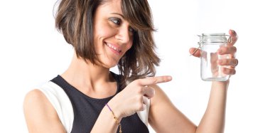 Beyaz arka plan üzerinde boş bir cam şişe tutan güzel bir kız 