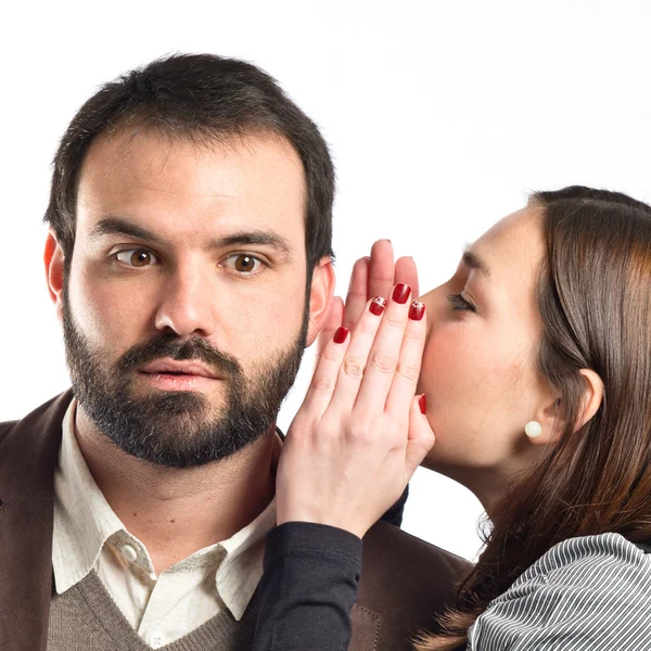 Junges Mädchen flüstert ihrem Freund über weißem Hintergrund zu — Stockfoto