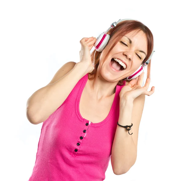 Chica joven escuchando música sobre fondo blanco — Foto de Stock