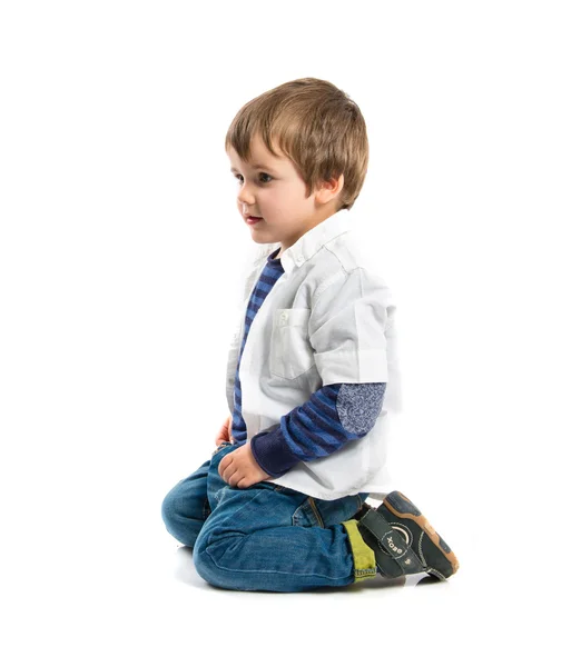 Blonde kid sitting on floor over white background — Stock Photo, Image