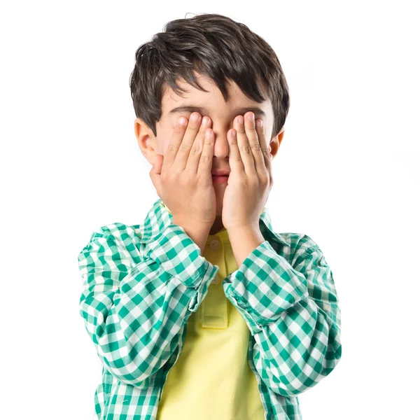 Мальчик закрывает глаза на белом фоне — стоковое фото