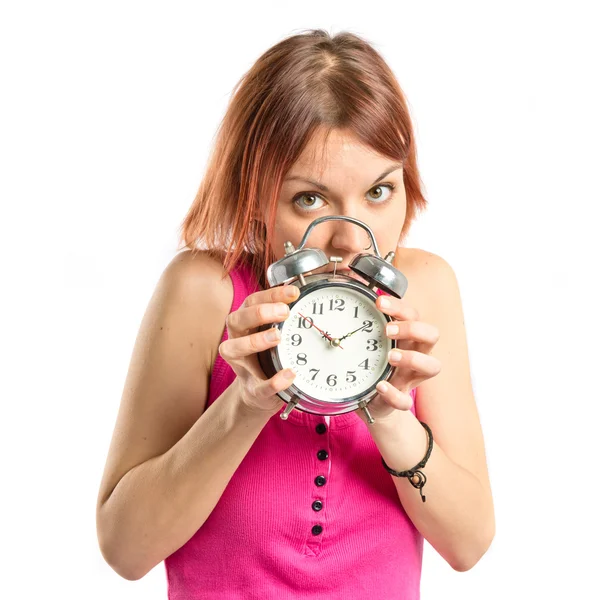 Chica pelirroja seria sosteniendo un reloj sobre fondo blanco — Foto de Stock