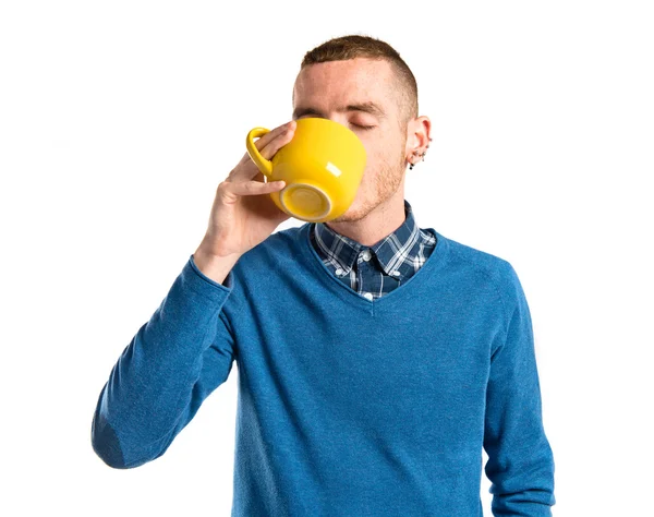 Молодой рыжий мужчина пьет кофе на белом фоне — стоковое фото