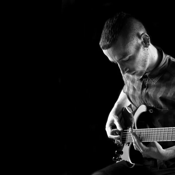 Mladý muž, hrál na kytaru na černém pozadí — Stock fotografie