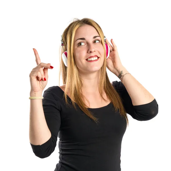 Joven chica rubia escuchando música sobre fondo blanco — Foto de Stock