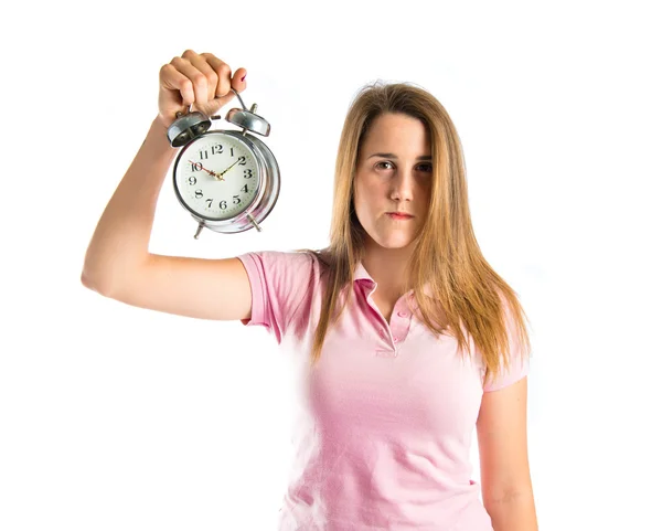 Серьёзная девушка держит часы на белом фоне — стоковое фото