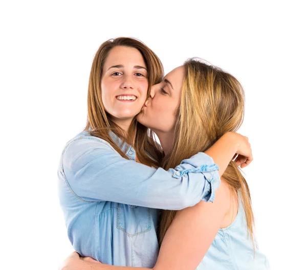 Girl giving kiss at her sister over white background — Stock Photo, Image