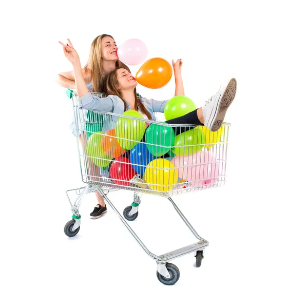 Chica con muchos globos dentro de carro de supermercado sobre fondo blanco — Foto de Stock