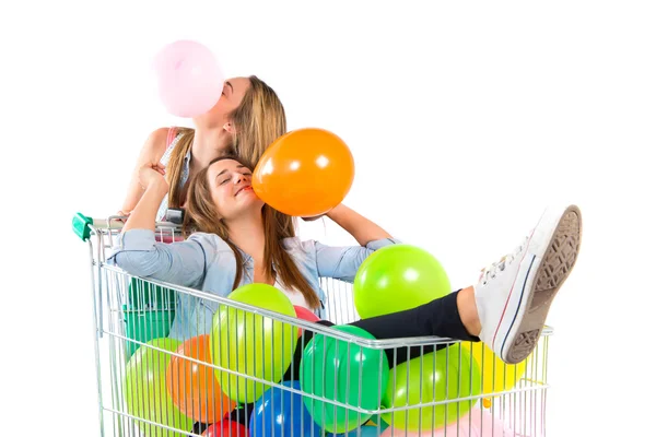 Menina com muitos balões dentro carrinho de supermercado sobre fundo branco — Fotografia de Stock
