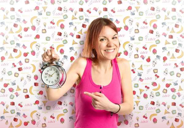 Gelukkig roodharige meisje houdt van een klok over leuke achtergrond — Stockfoto