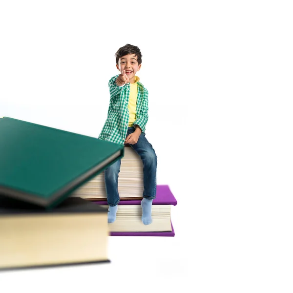Kind auf mehreren Büchern vor weißem Hintergrund lizenzfreie Stockbilder