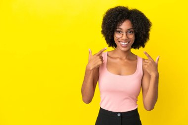 Sarı arka planda izole edilmiş genç Afrikalı Amerikalı bir kadın baş parmak işareti yapıyor.