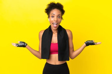 Genç Afrikalı sporcu kadın sarı arka planda şok olmuş yüz ifadesiyle izole edilmiş.