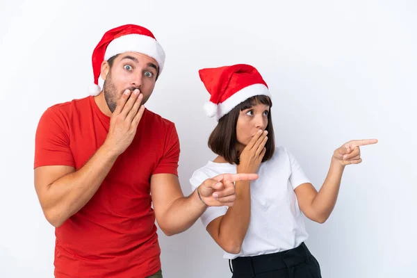 Junges Paar Mit Weihnachtsmütze Isoliert Auf Weißem Hintergrund Zeigt Mit — Stockfoto