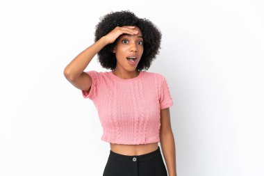 Beyaz arka planda izole edilmiş genç Afrikalı Amerikalı kadın yan tarafa bakarken sürpriz jest yapıyor.