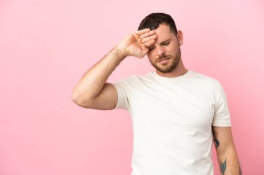 Genç Brezilyalı adam pembe arka planda izole edilmiş, yorgun ve hasta bir ifadeyle.