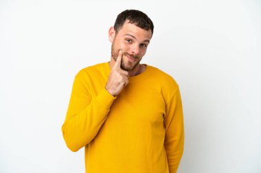 Genç Brezilyalı adam beyaz arka planda izole edilmiş ve düşünüyor.