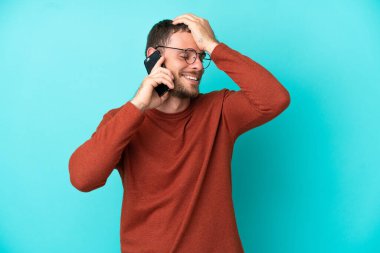 Mavi arka planda izole edilmiş cep telefonu kullanan genç Brezilyalı bir adam bir şey fark etti ve çözümü arıyor.