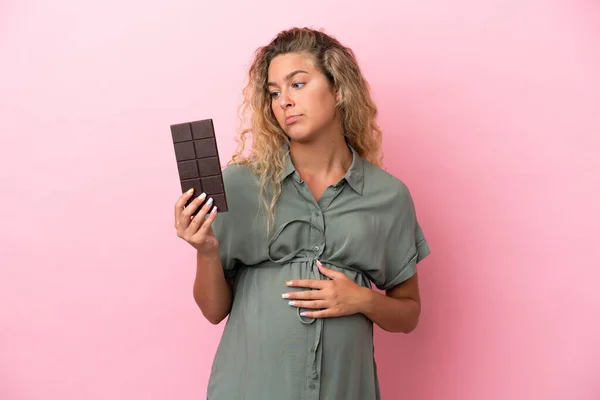 Dívka Kudrnaté Vlasy Izolované Růžovém Pozadí Těhotné Drží Čokoládu Hladem — Stock fotografie