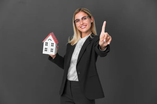 Blond Uruguayaans Meisje Met Een Huis Speelgoed Geïsoleerd Zwarte Achtergrond — Stockfoto