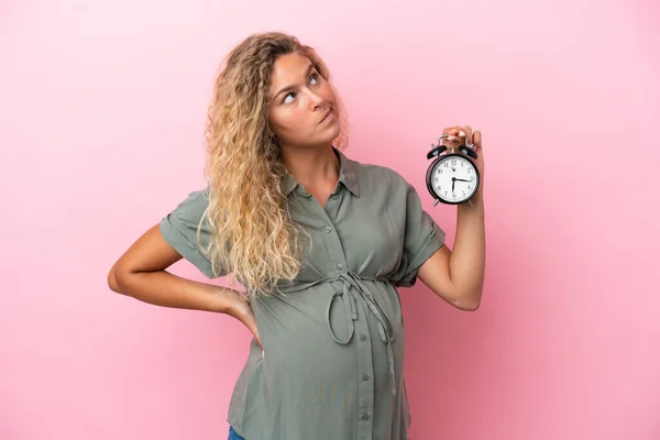 Chica Con Pelo Rizado Aislado Fondo Rosa Embarazada Celebración Reloj — Foto de Stock