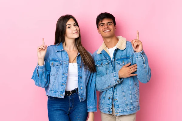 Casal Jovem Sobre Fundo Rosa Isolado Mostrando Levantando Dedo Sinal — Fotografia de Stock