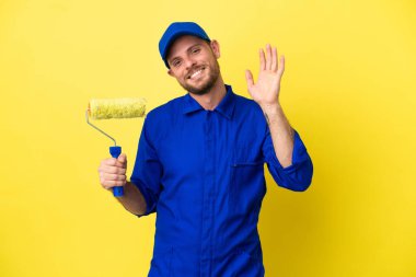 Ressam Brezilyalı izole edilmiş sarı arka planda mutlu bir ifadeyle selamlıyor.