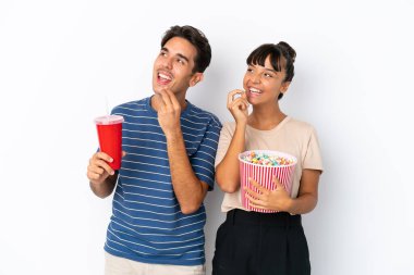 Beyaz arka planda izole edilmiş genç melez arkadaşlar ellerinde koca bir kova patlamış mısır tutuyorlar.