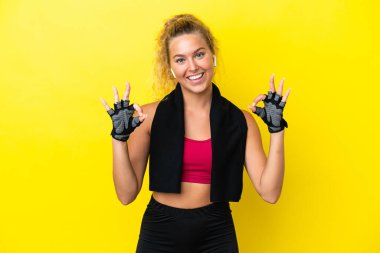 Sarı arka planda izole edilmiş havlusu olan sporcu kadın parmaklarıyla 