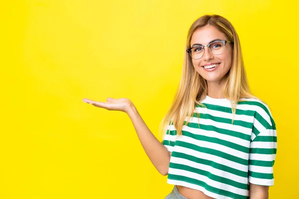 Blond Uruguayan Flicka Isolerad Gul Bakgrund Håller Copyspace Imaginära Handflatan — Stockfoto