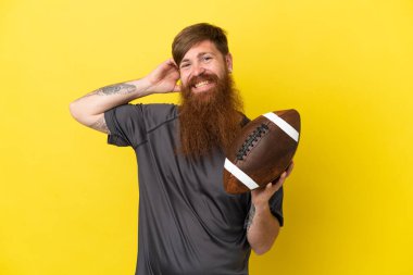 Kızıl saçlı beyaz adam sarı arka planda ragbi oynuyor. 