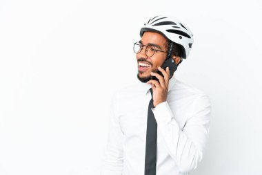 Beyaz arka planda izole edilmiş bisiklet kaskı tutan genç Latin bir adam cep telefonuyla sohbet ediyor.
