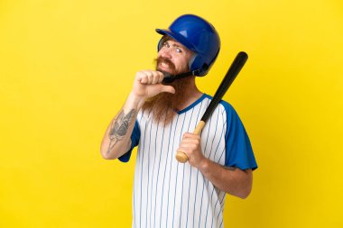 Kask ve yarasalı kızıl saçlı beyzbolcu sarı arka planda kendini beğenmiş ve gururlu.