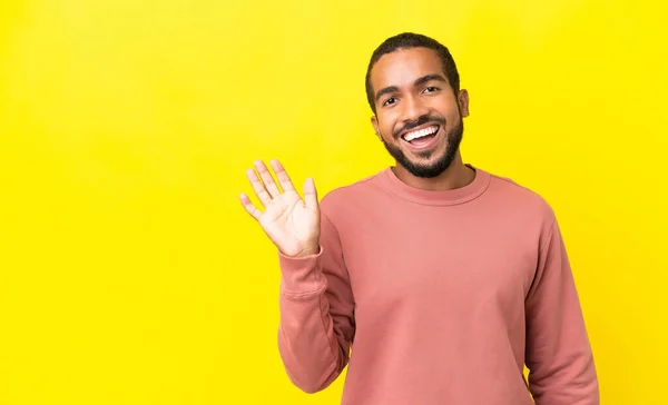 Junger Lateinischer Mann Auf Gelbem Hintergrund Salutiert Mit Fröhlichem Gesichtsausdruck — Stockfoto
