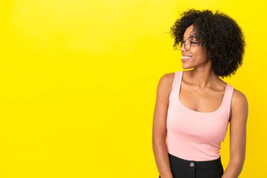 Sarı arka planda izole edilmiş genç Afrikalı Amerikalı kadın.