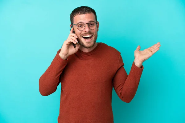 Mladý Brazilský Muž Pomocí Mobilního Telefonu Izolované Modrém Pozadí Šokovaným — Stock fotografie