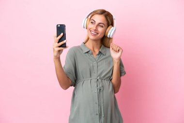 Genç Uruguaylı kadın mavi arka planda izole edilmiş hamile ve selfie çekiyor.