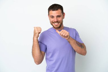 Beyaz arka planda izole edilmiş genç Brezilyalı bir adam bir ürün sunmak için kenarı işaret ediyor