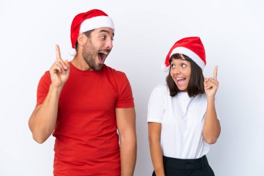 Beyaz arka planda izole edilmiş Noel şapkalı genç bir çift parmak kaldırarak çözümü anlamaya çalışıyor.