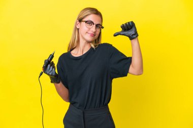 Dövme sanatçısı Uruguaylı kadın sarı arka planda kendini beğenmiş ve gururlu.