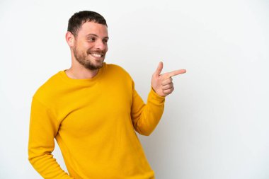 Beyaz arka planda izole edilmiş genç Brezilyalı bir adam parmak göstererek bir ürün sunuyor.