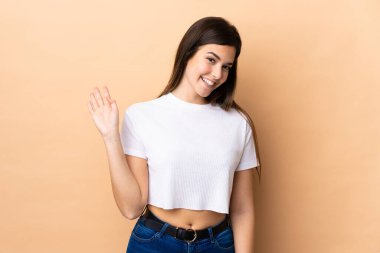 Genç Brezilyalı kız, izole edilmiş arka planda mutlu bir ifadeyle selamlıyor.