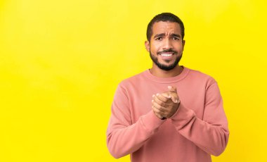 Sarı arka planda yalnız yaşayan genç latin adam gülüyor.