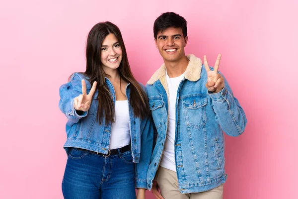 Casal Jovem Sobre Fundo Rosa Isolado Sorrindo Mostrando Sinal Vitória — Fotografia de Stock