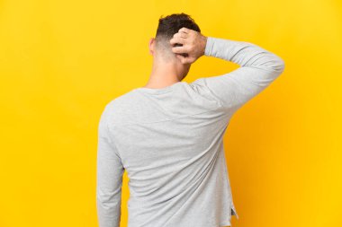 Beyaz tenli yakışıklı adam sarı arka planda izole edilmiş ve düşünüyor.