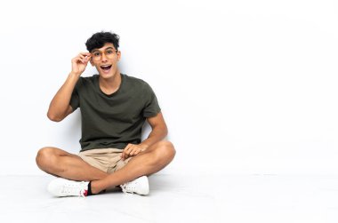 Genç Arjantinli adam gözlükleriyle yerde oturuyor ve şaşırdı.