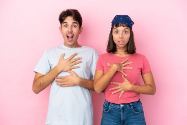 Pembe arka planda izole edilmiş genç çift sağa bakarken şaşırmış ve şok olmuştu.